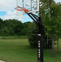 A basketball hoop is sitting in the middle of a grassy field.