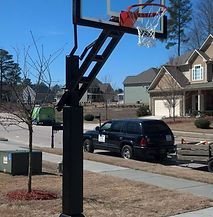 A black suv is parked in front of a basketball hoop in a driveway.
