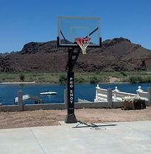 A basketball hoop is sitting next to a lake with mountains in the background.
