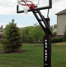 A basketball hoop is sitting in the middle of a lush green field.