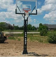 A basketball hoop is sitting in the middle of a dirt field.