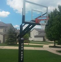 A basketball hoop is sitting in the middle of a lush green yard.