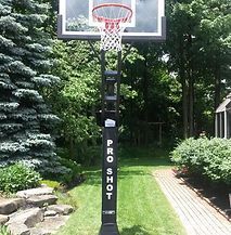 A basketball hoop is sitting in the middle of a lush green field.