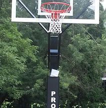 A basketball hoop is surrounded by trees in a park.