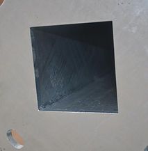 A black square with a hole in the middle on a concrete surface.