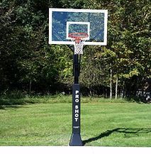 A basketball hoop is sitting on top of a lush green field.
