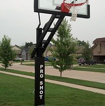 A basketball hoop is sitting in the middle of a lush green field.