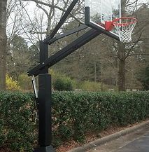 A basketball hoop is sitting on the side of a road in a park.