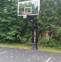 A basketball hoop is sitting on top of a concrete court surrounded by trees.