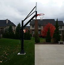 A basketball hoop is sitting in front of a house in a backyard.