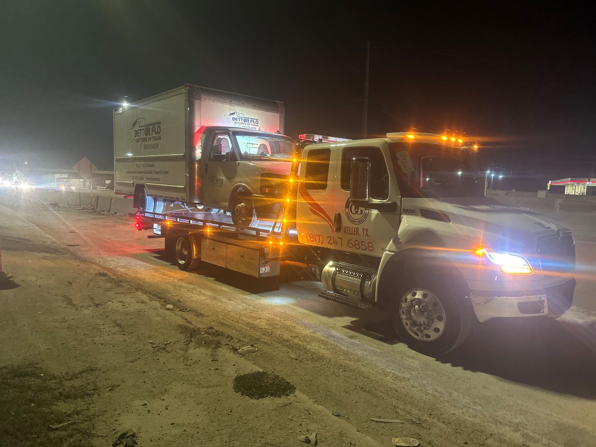 Three white trucks and a white van are parked in front of a building.