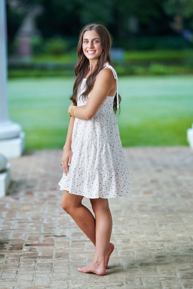 A woman in a white dress is standing on a brick sidewalk.