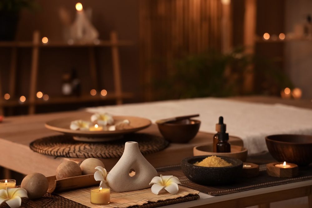 A table in a spa with candles and flowers on it.