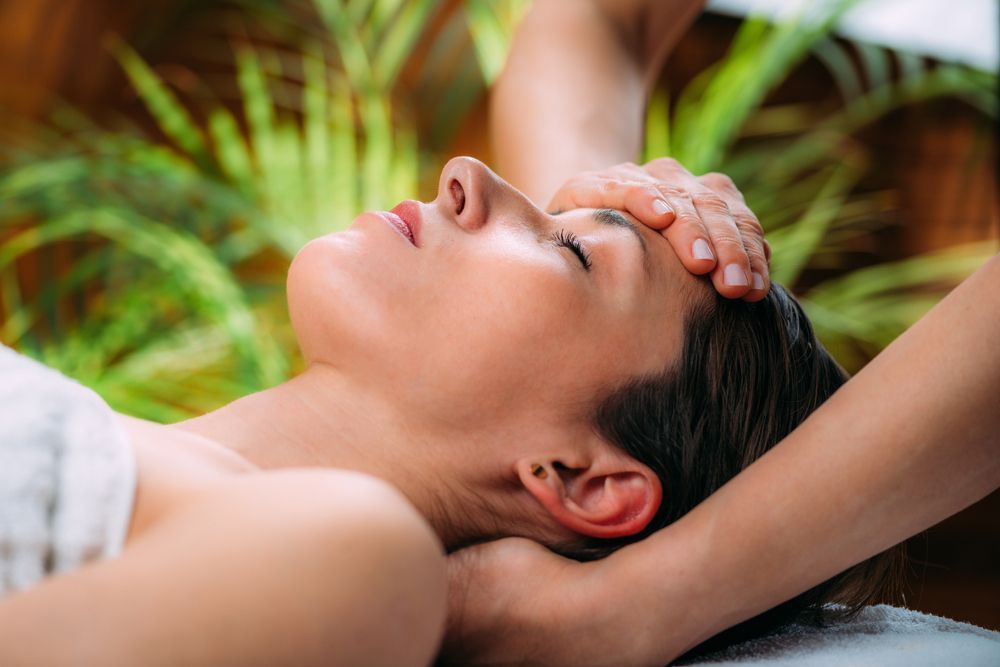A woman is getting a head massage at a spa.