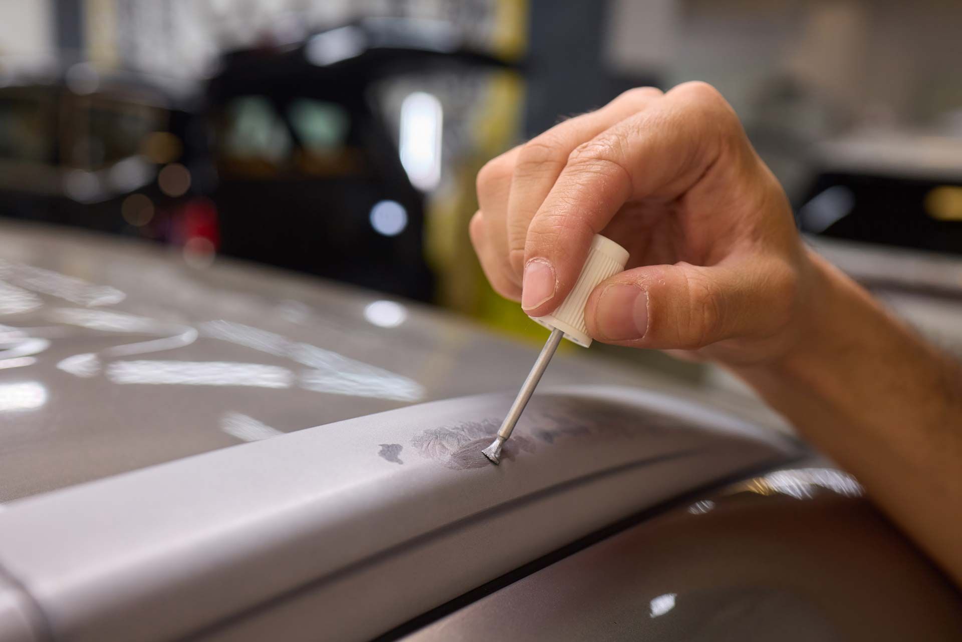 Hand applying paint to a car roof rack in a workshop, possibly for touch-up repair.