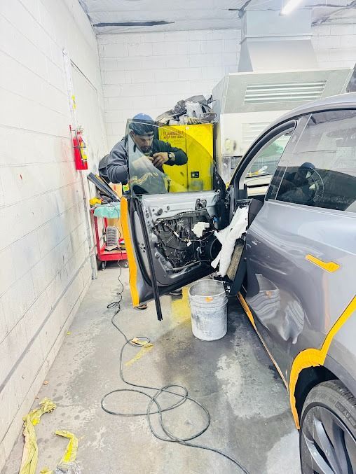 Person working on a car door in a garage.
