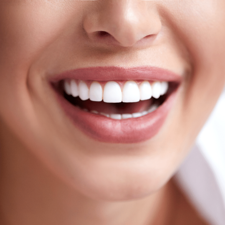 A close up of a woman 's smile with white teeth and pink lips.