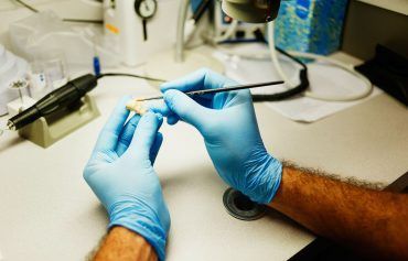 A person wearing blue gloves is working on a piece of equipment.