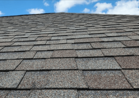 Close-up of a gray shingled roof against a blue sky