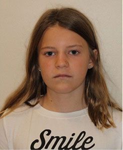 A young girl wearing a white shirt that says smile