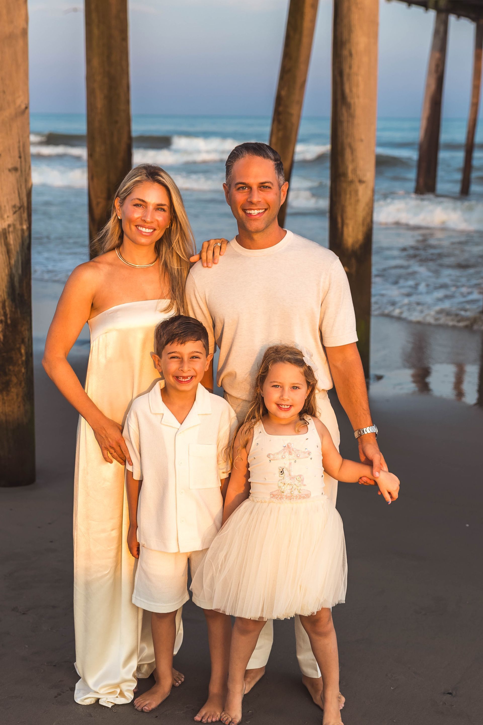Dr. Jordan Cogan with his wife, Amber, and their children, Reign and Vida, on the beach near a pier