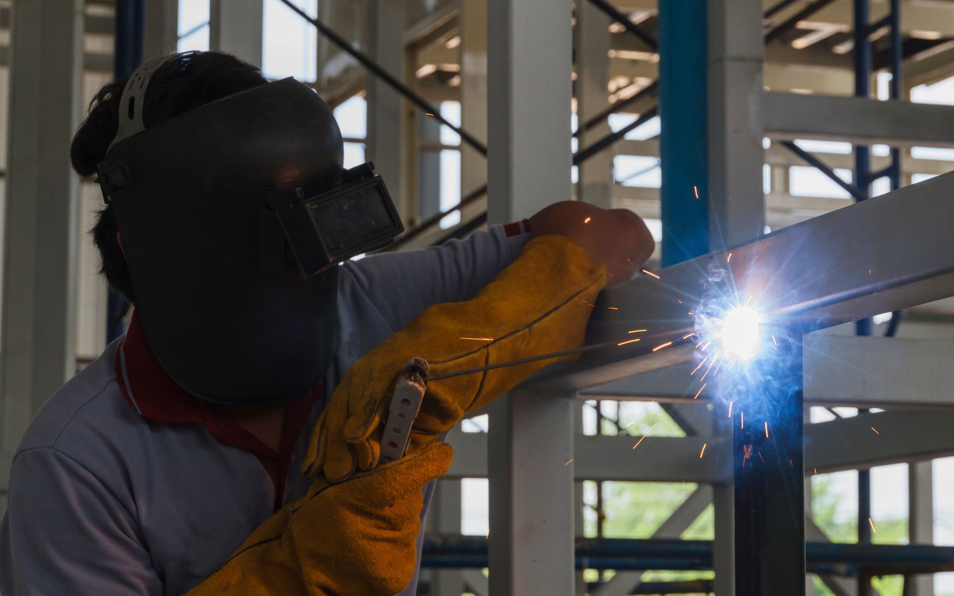 A man is welding a piece of metal in a factory.