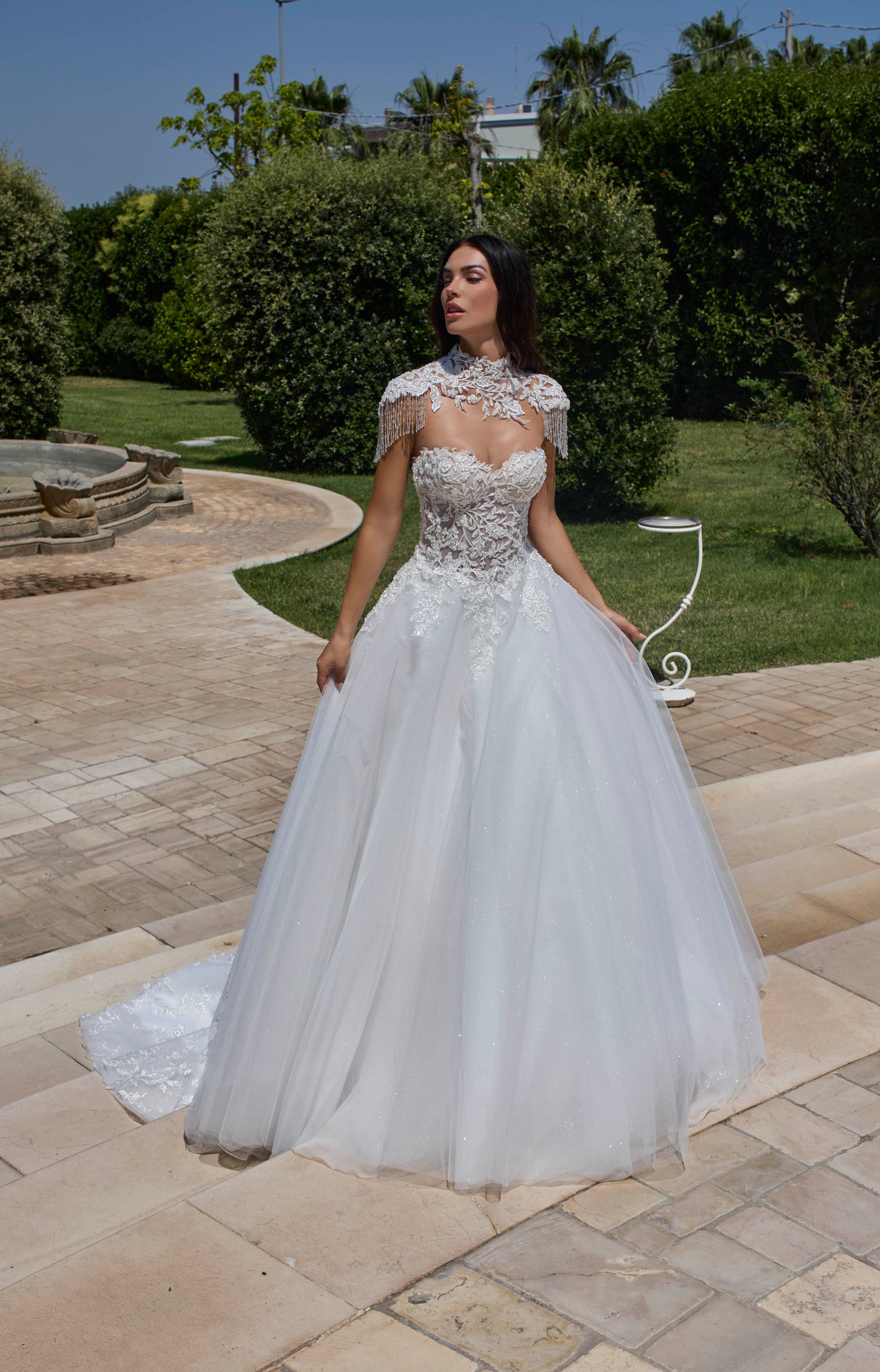 Donna in abito da ballo bianco, all'aperto. L'abito ha un corpetto decorato con perline e una gonna in tulle.