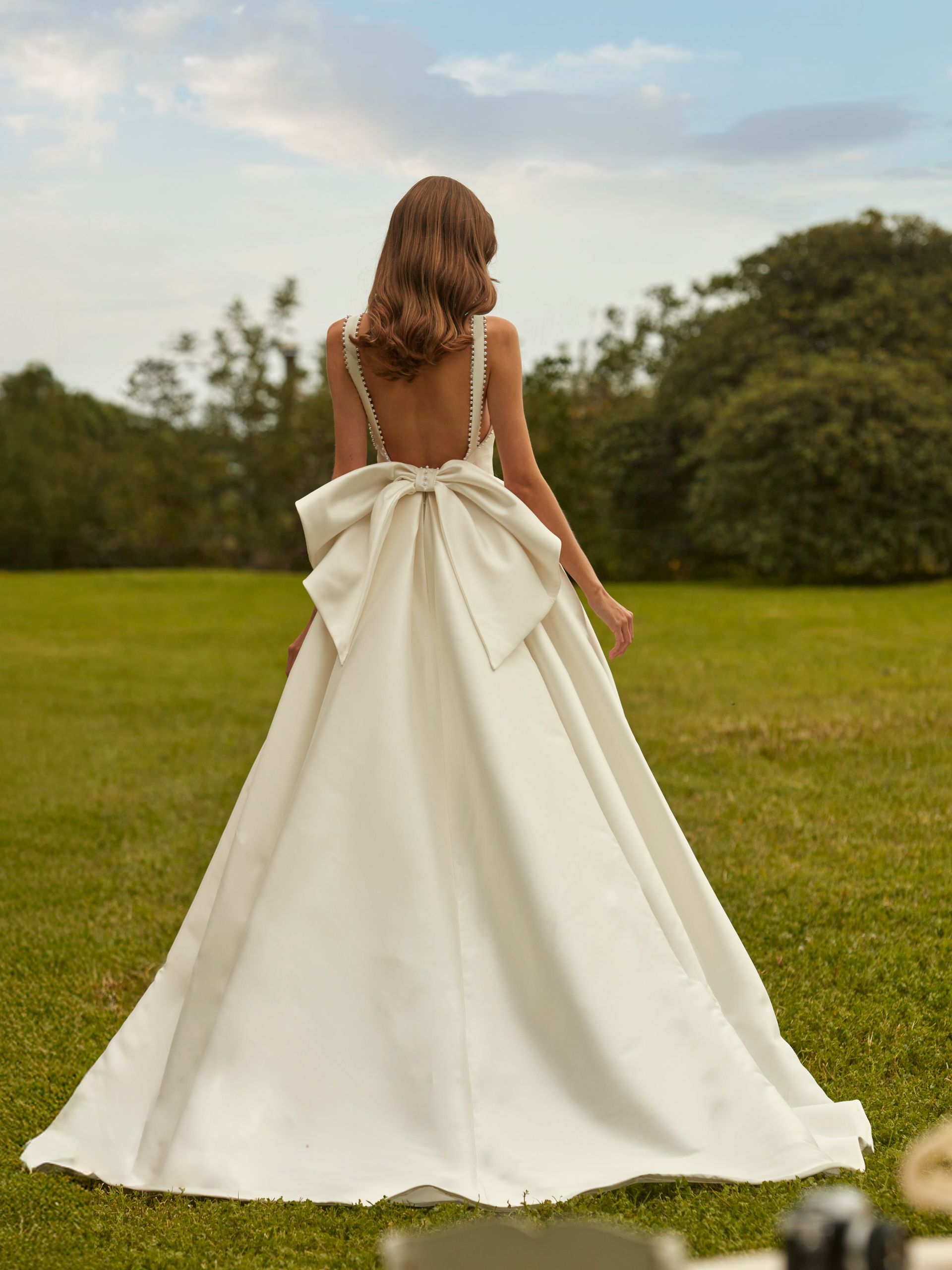 Abiti da sposa esposti sugli scaffali di un negozio di abiti da sposa, la luce del sole filtra attraverso una finestra.