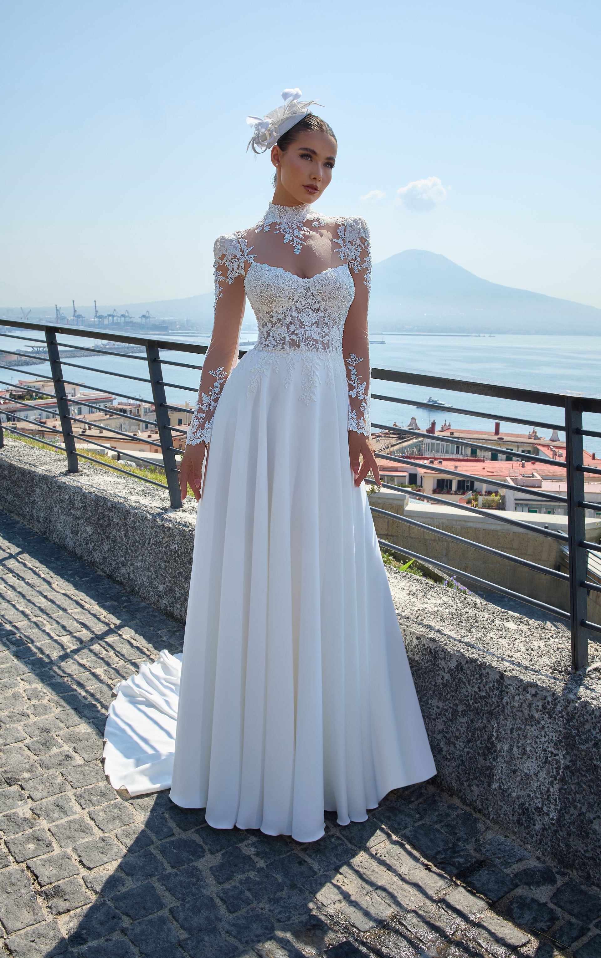 Una donna in abito da sposa bianco con corpetto in pizzo, maniche lunghe e gonna svolazzante è in piedi all'aperto