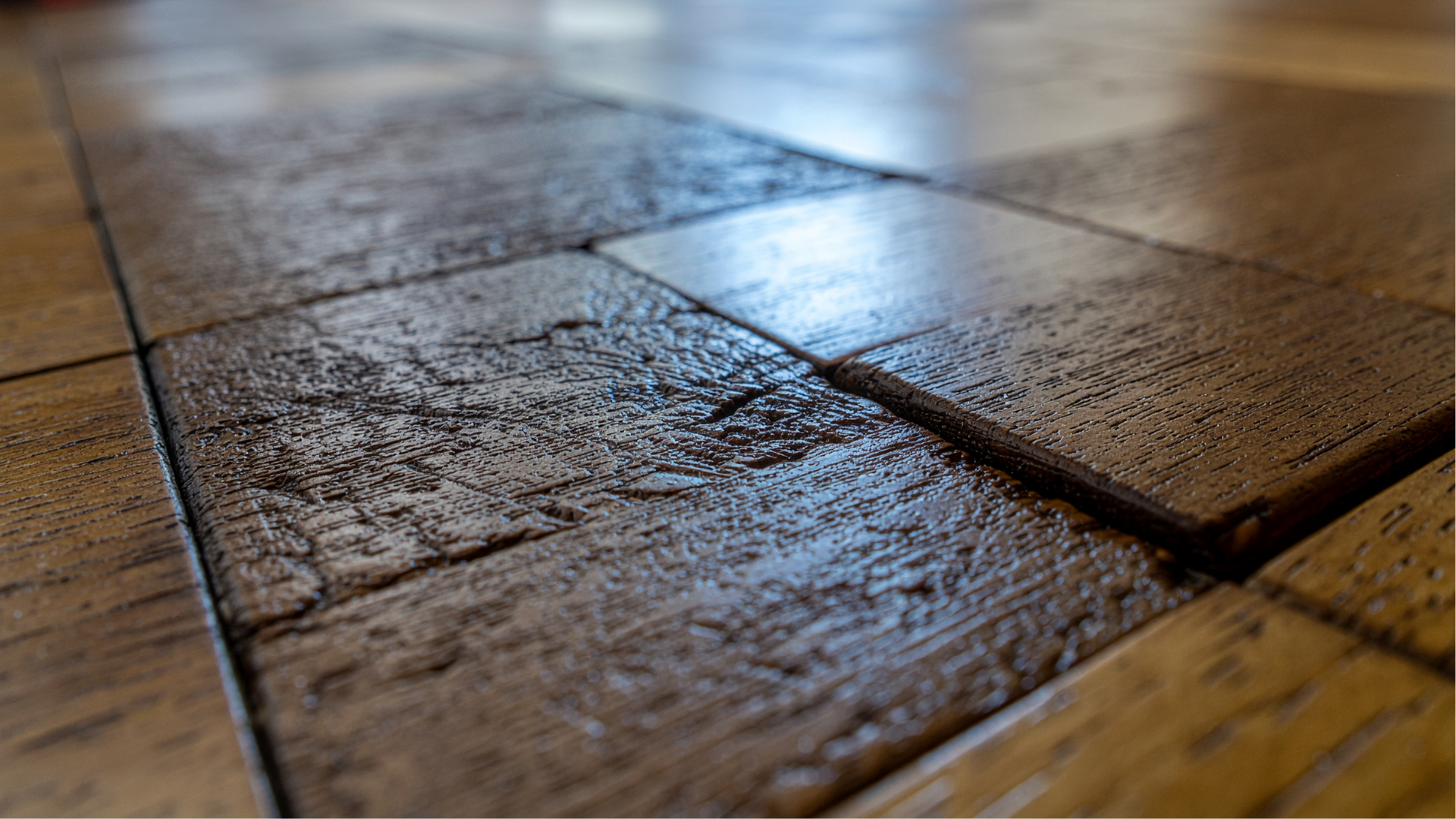 Close-up of textured wooden floor tiles with a seam and glossy light reflection