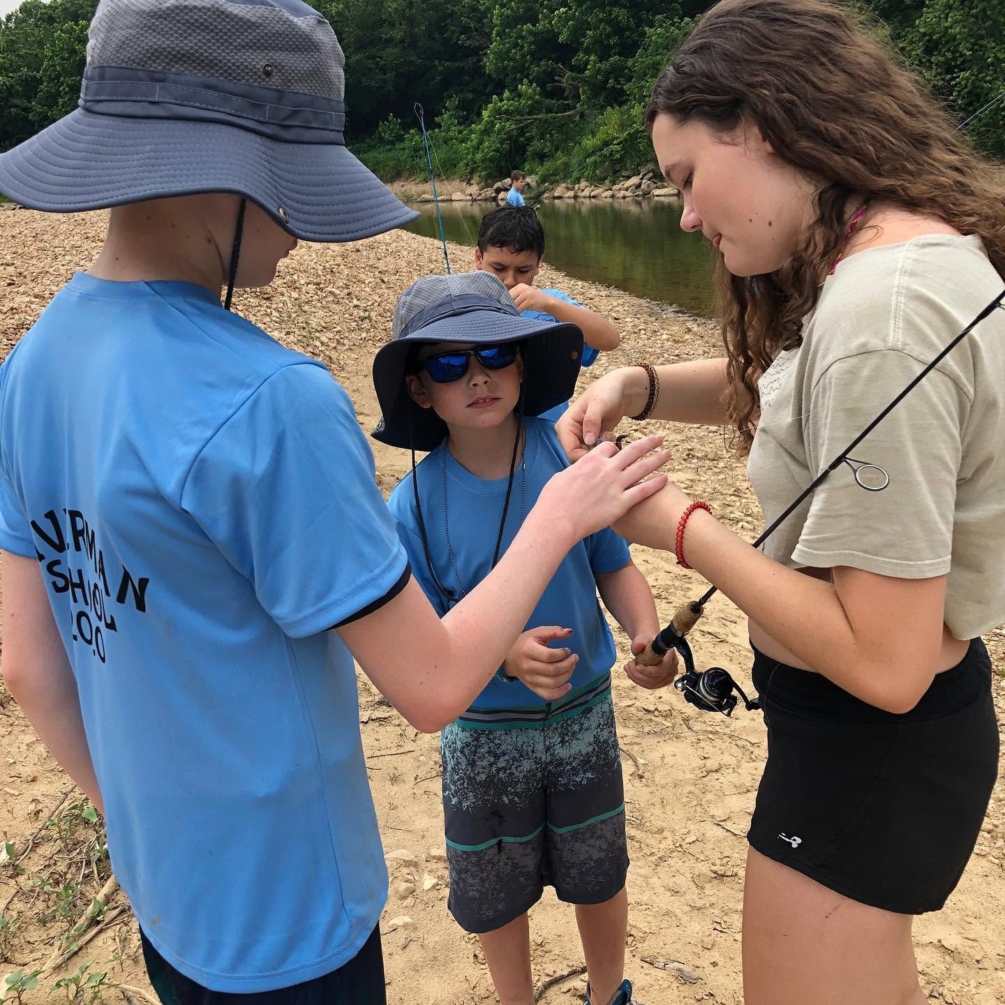 Three people on a sandy beach handle a small fish together