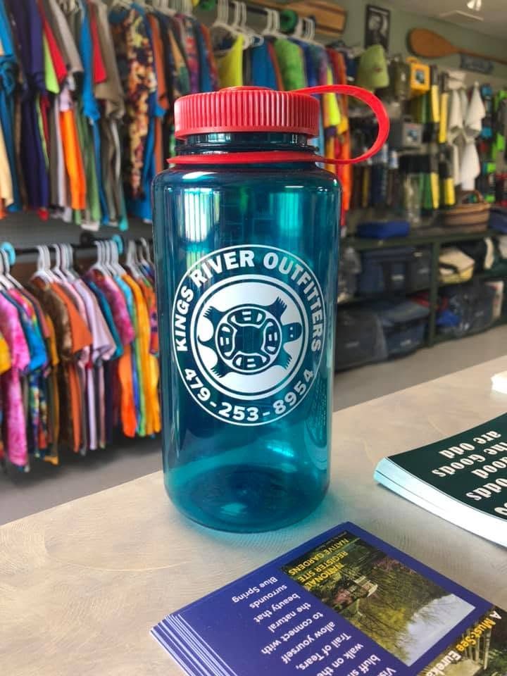 Blue water bottle with red lid and “Rogers River Outfitters” logo on a shop counter