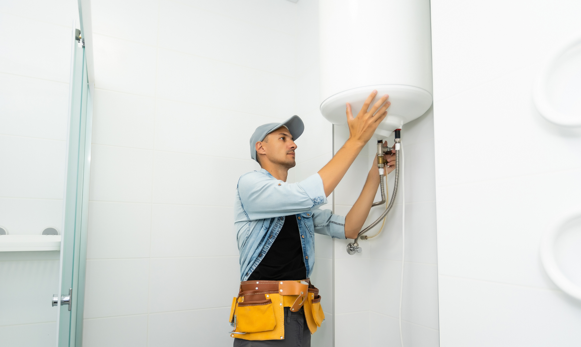 Technician adjusting a wall-mounted water heater in a bright room Technician adjusting a wall-mounted water heater in a bright room