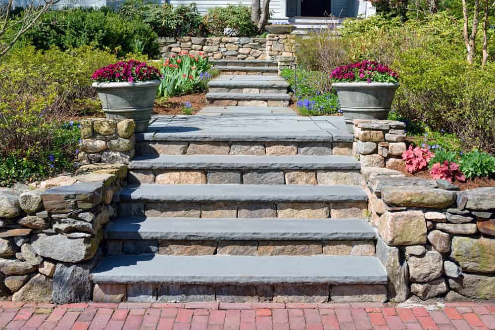 A Stone Staircase Leading up To a House with Flowers in Pots — Peter Phillips Landscape Design in Bomaderry, NSW