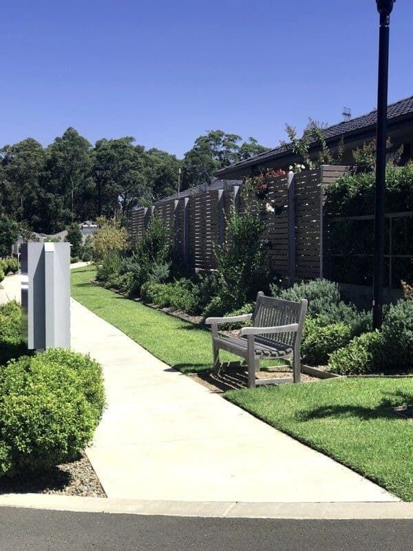 A Bench Is Sitting on A Sidewalk Next to A Fence — Peter Phillips Landscape Design in Nowra, NSW