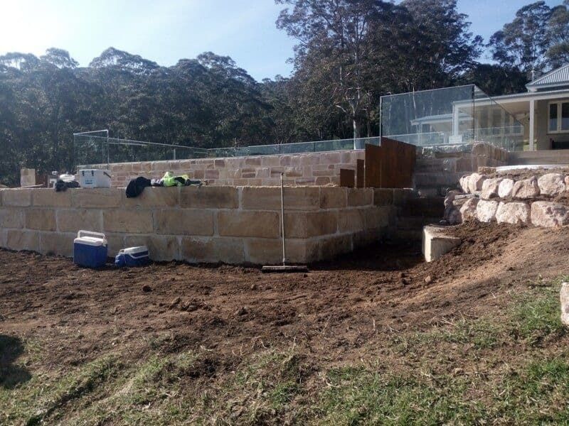 A Large Stone Wall Is Being Built in Front of A House — Peter Phillips Landscape Design in Kangaroo Valley, NSW