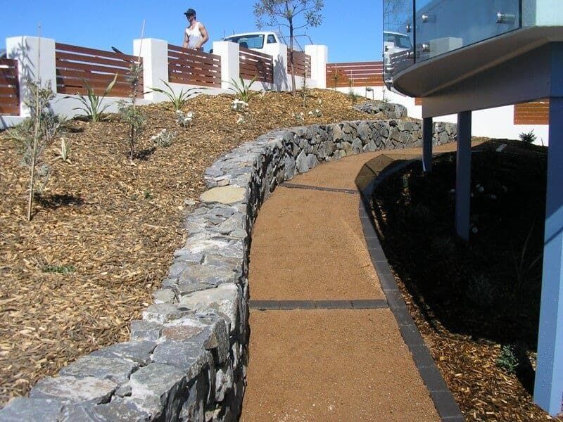 A Stone Wall Along a Walkway Leading to A House — Peter Phillips Landscape Design in Nowra, NSW