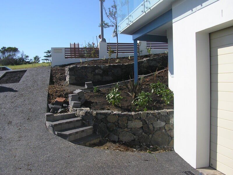 A Driveway Leading to A House with A White Garage Door — Peter Phillips Landscape Design in Bomaderry, NSW