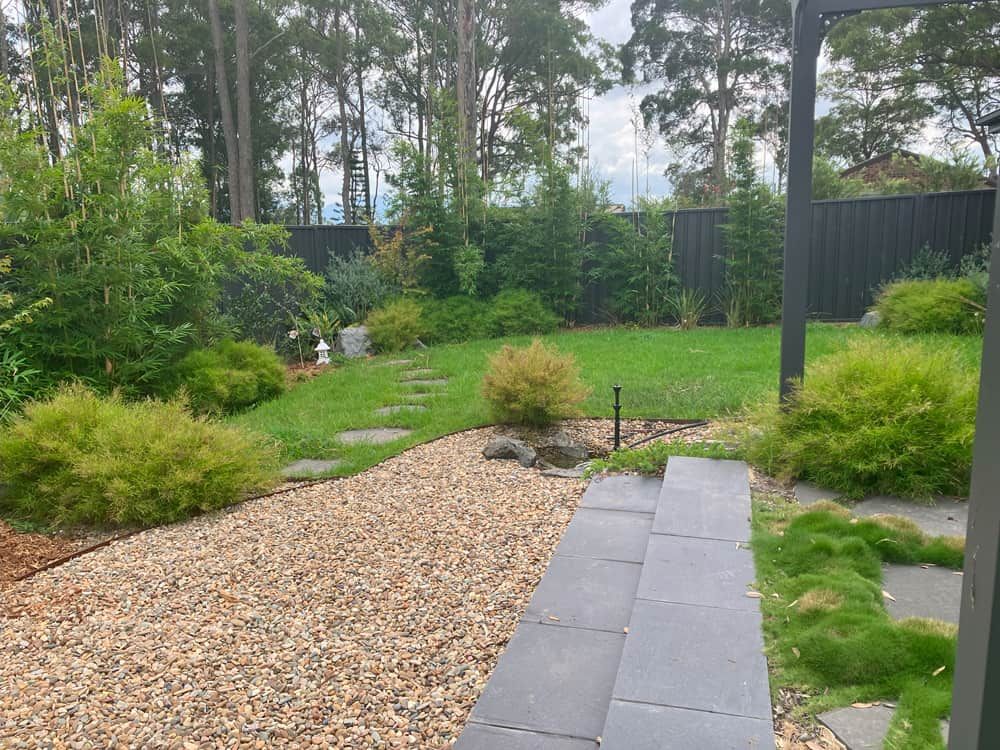 A Gravel Path Leading to a Lush Green Yard With Trees — Peter Phillips Landscape Design in Vincentia, NSW