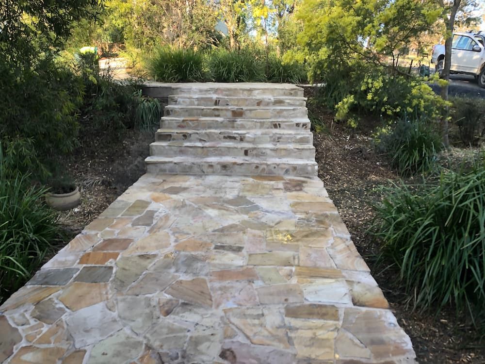 A Stone Walkway With Stairs Leading Up to a Lush Green Forest — Peter Phillips Landscape Design in Bomaderry, NSW