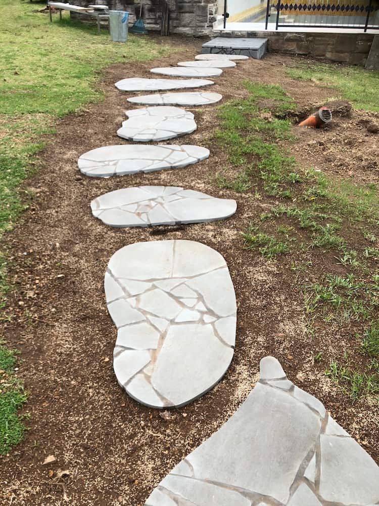 A Stone Walkway is Lined Up in the Grass in a Backyard — Peter Phillips Landscape Design in Bomaderry, NSW
