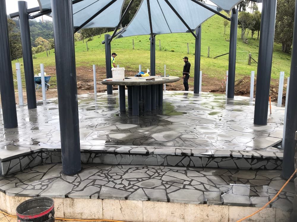 A Man is Standing Under an Umbrella on a Patio — Peter Phillips Landscape Design in Bomaderry, NSW