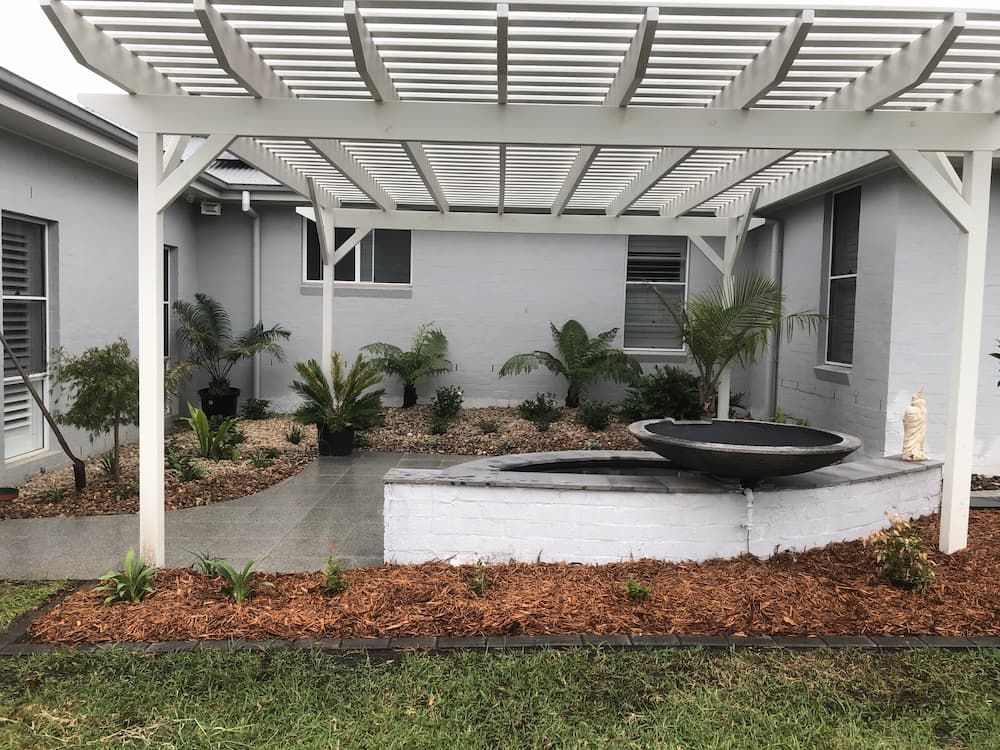 A White Pergola is Sitting in the Backyard of a House — Peter Phillips Landscape Design in Sussex Inlet, NSW