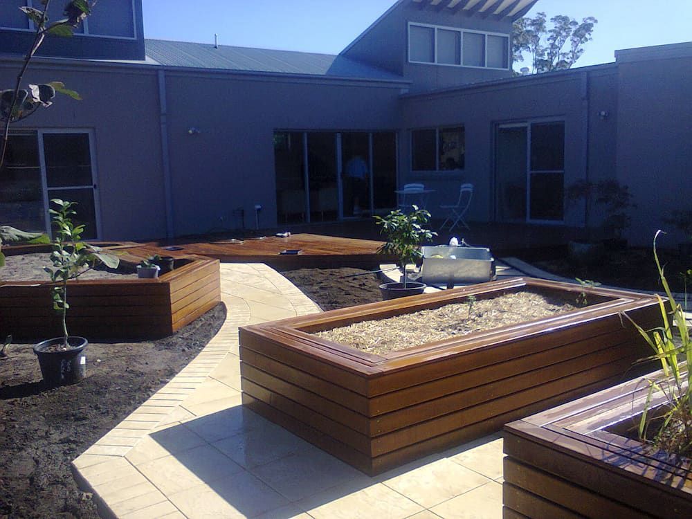 A House With a Walkway and Wooden Planters in Front of It — Peter Phillips Landscape Design in Bomaderry, NSW