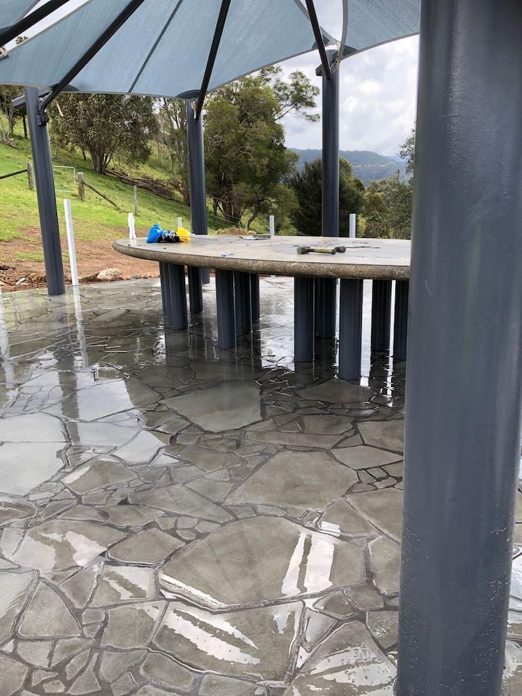 A Concrete Patio With a Blue Umbrella and a Reflection of Trees — Peter Phillips Landscape Design in Bomaderry, NSW