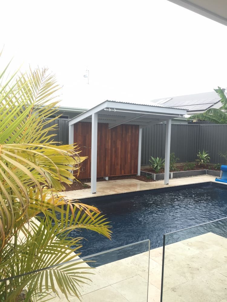 A Swimming Pool With a Pergola and a Palm Tree in the Foreground — Peter Phillips Landscape Design in Bomaderry, NSW