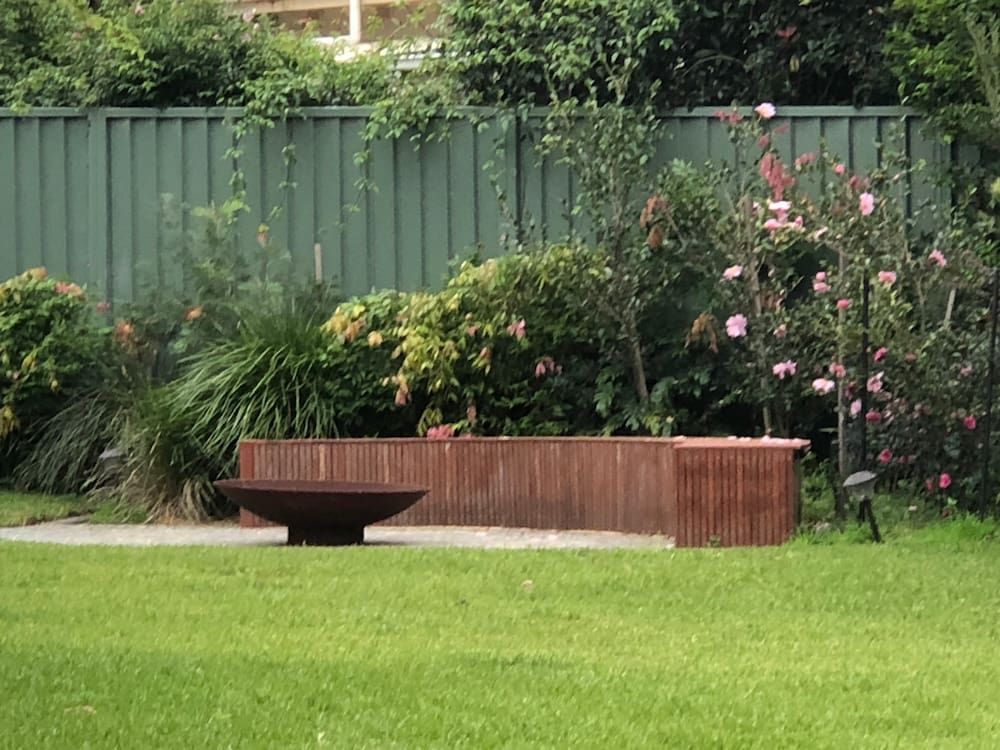A Fire Pit is in the Middle of a Lush Green Lawn — Peter Phillips Landscape Design in Bomaderry, NSW