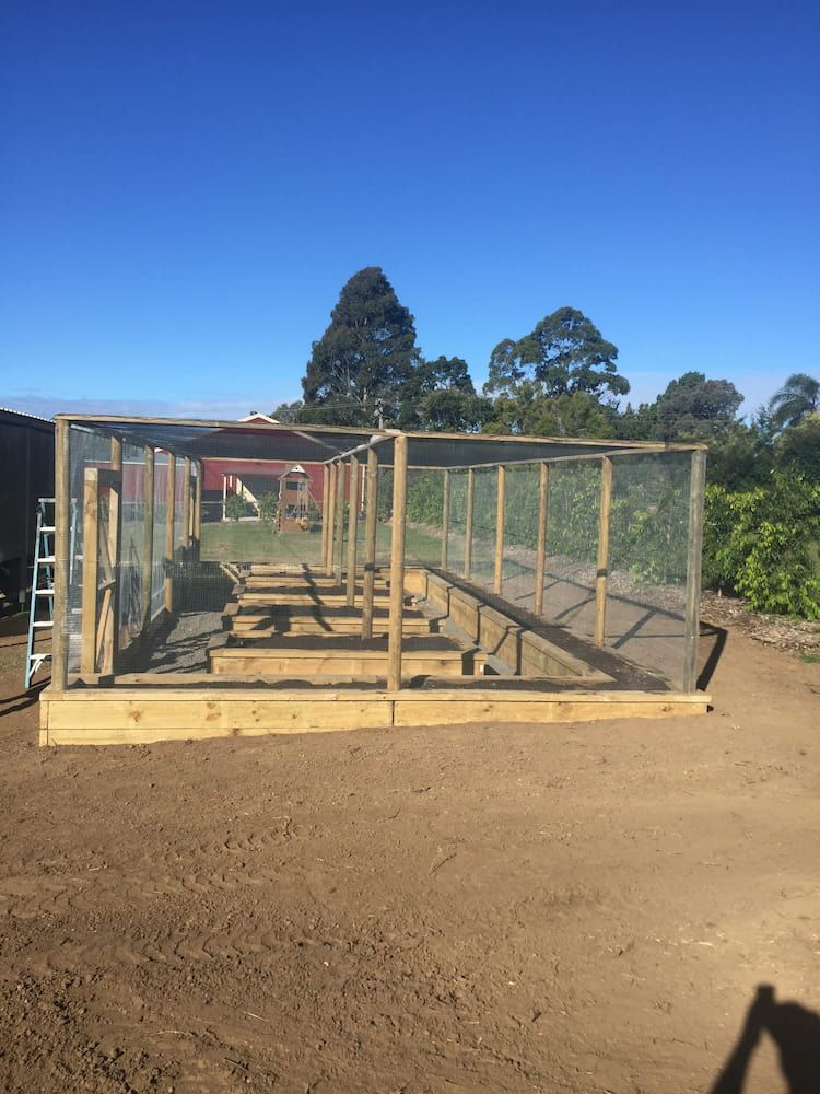 A Wooden Fence is Sitting in the Middle of a Dirt Field — Peter Phillips Landscape Design in Bomaderry, NSW
