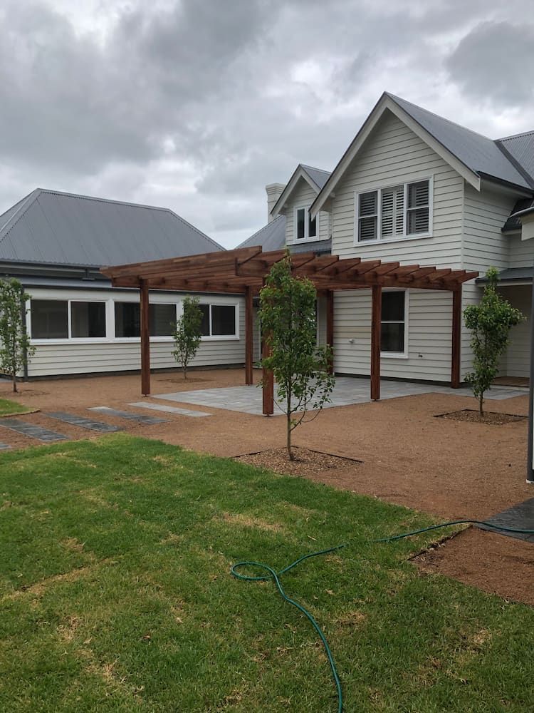 A Large White House With a Pergola in Front of It — Peter Phillips Landscape Design in Bomaderry, NSW