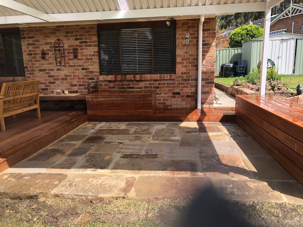A Brick House With a Wooden Deck and a Bench in Front of It — Peter Phillips Landscape Design in Bomaderry, NSW